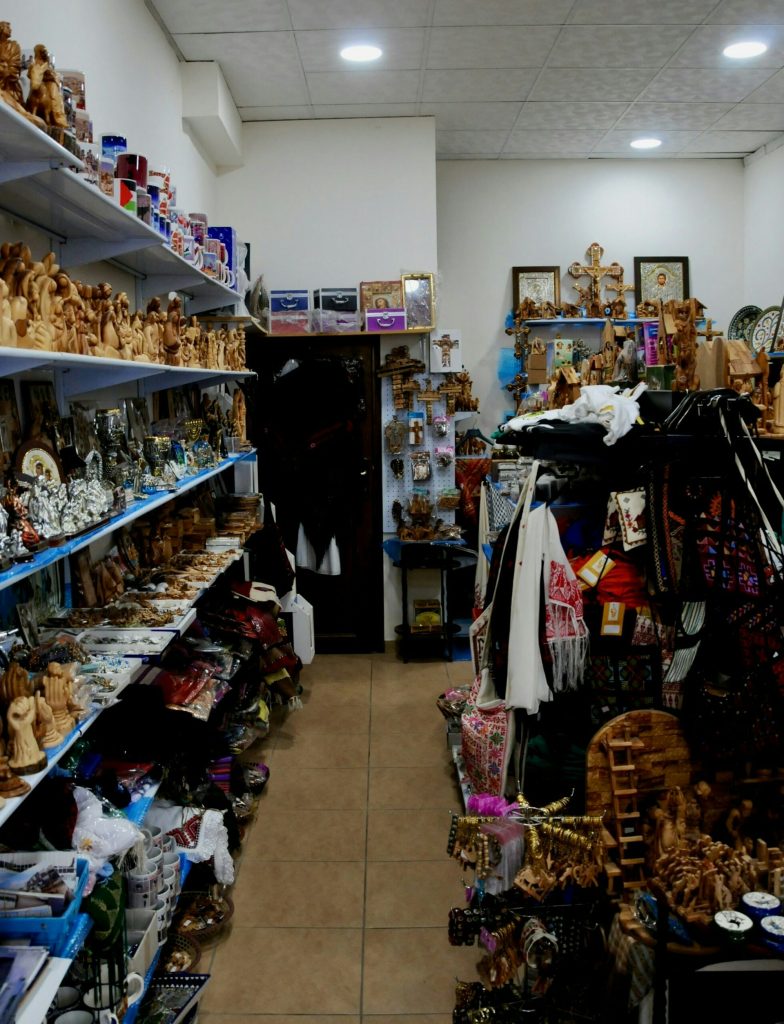 En smal butiksgång fylld med hyllor med souvenirer, trähantverk, textilier och prydnadsföremål.