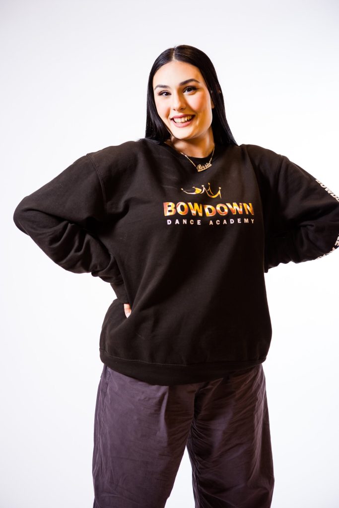 Kvinna som står i svarta kläder ler mot kameran.