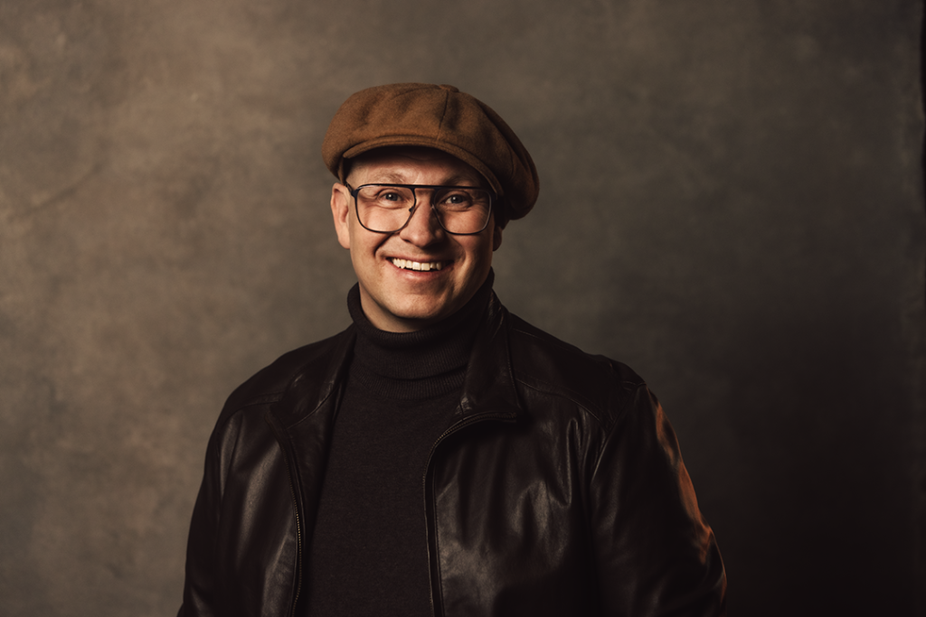 En man med skinnjacka och keps