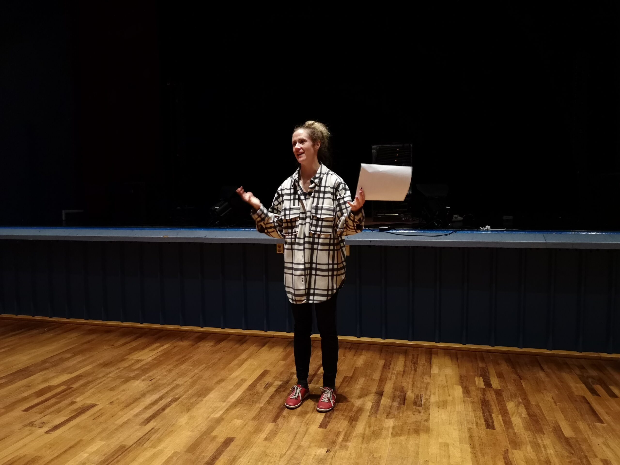 en kvinna som står på ett trägolv framför en mikrofon.
