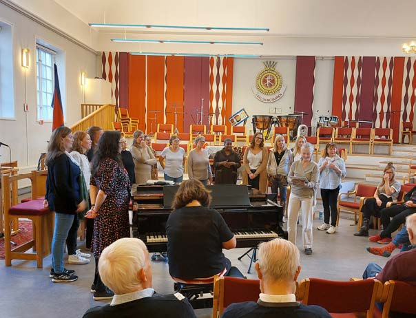 en grupp människor som står framför ett piano.