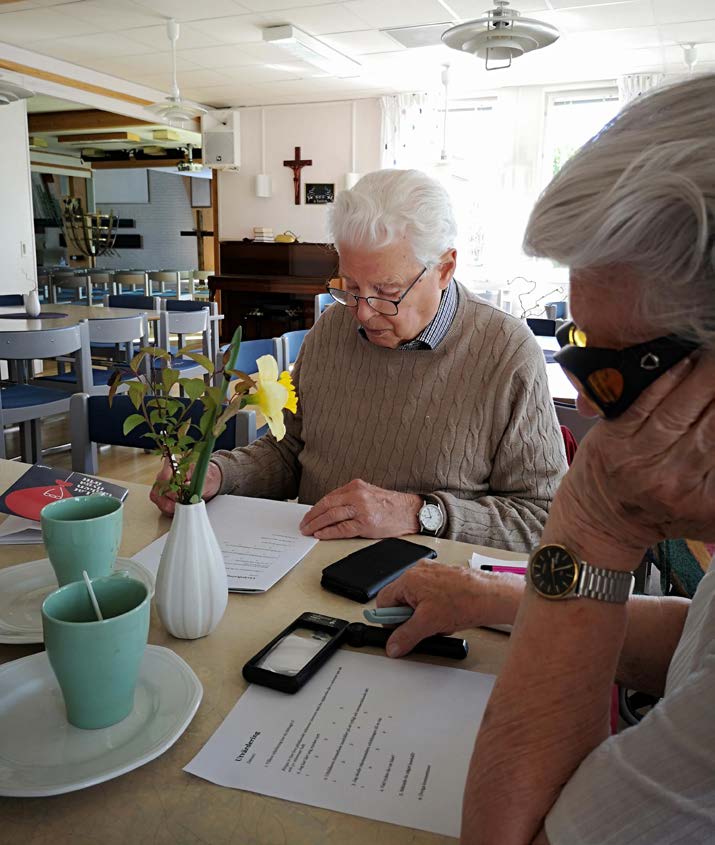 ett par personer som sitter vid ett bord med sina mobiltelefoner