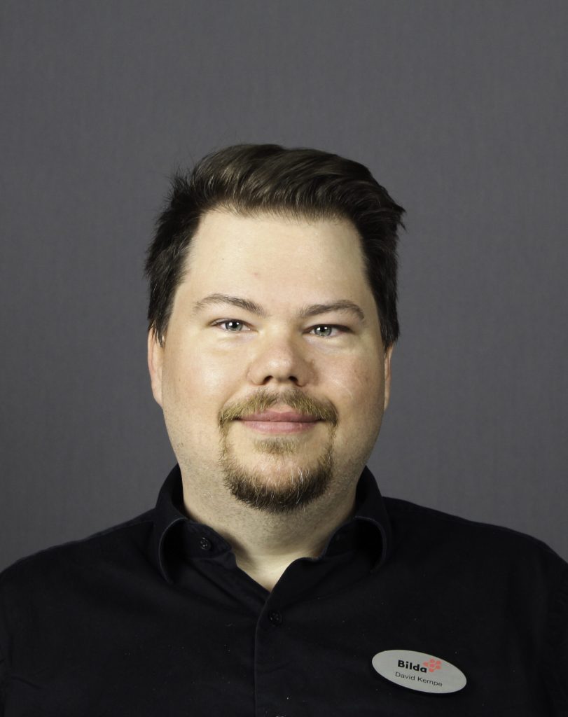 Porträttbild på David Kempe i en svart skjorta ler lite mot kameran.