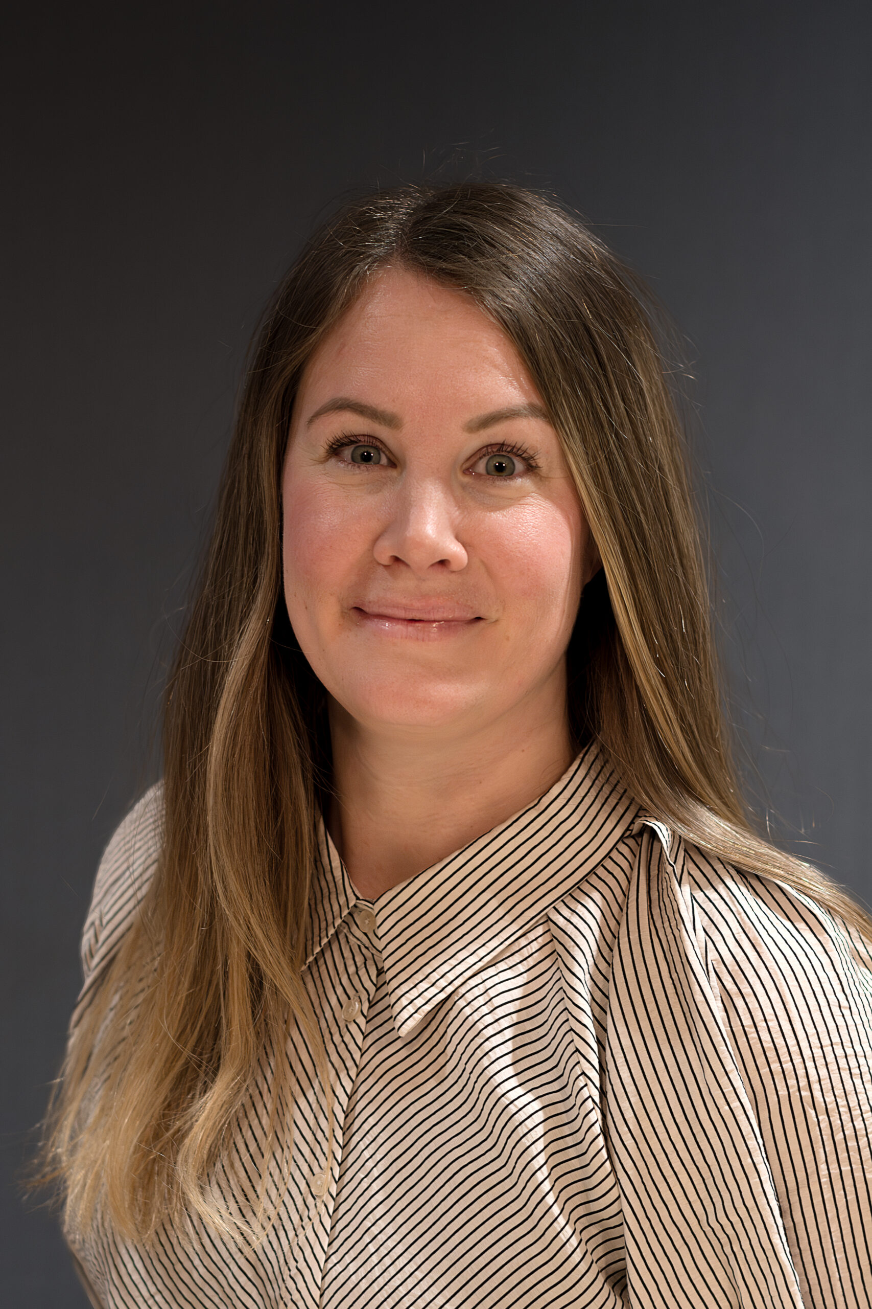 En kvinna i randig skjorta poserar för ett foto.