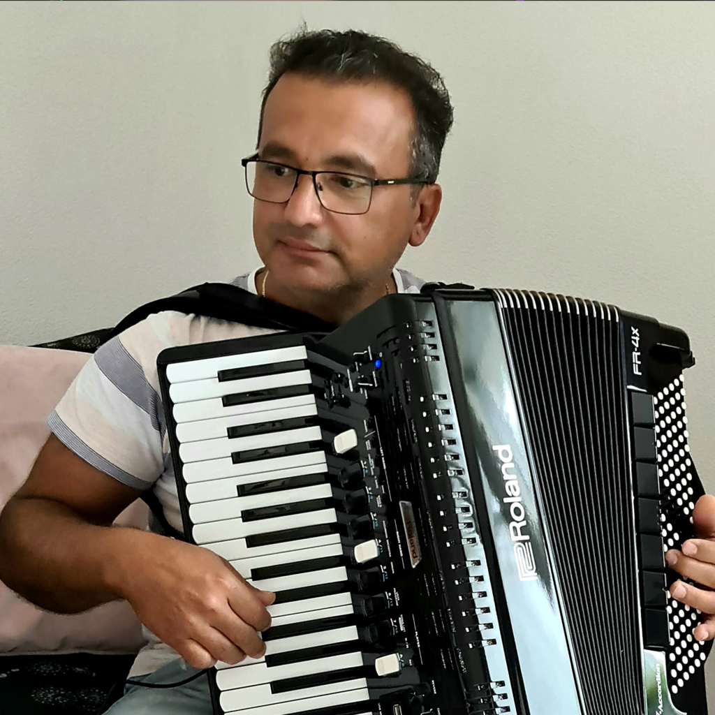 En man som sitter på en soffa och håller ett dragspel.