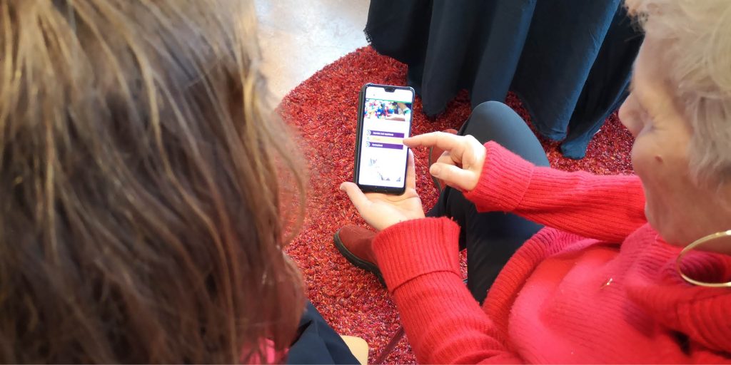 En kvinna visa en annan person något på en mobiltelefon