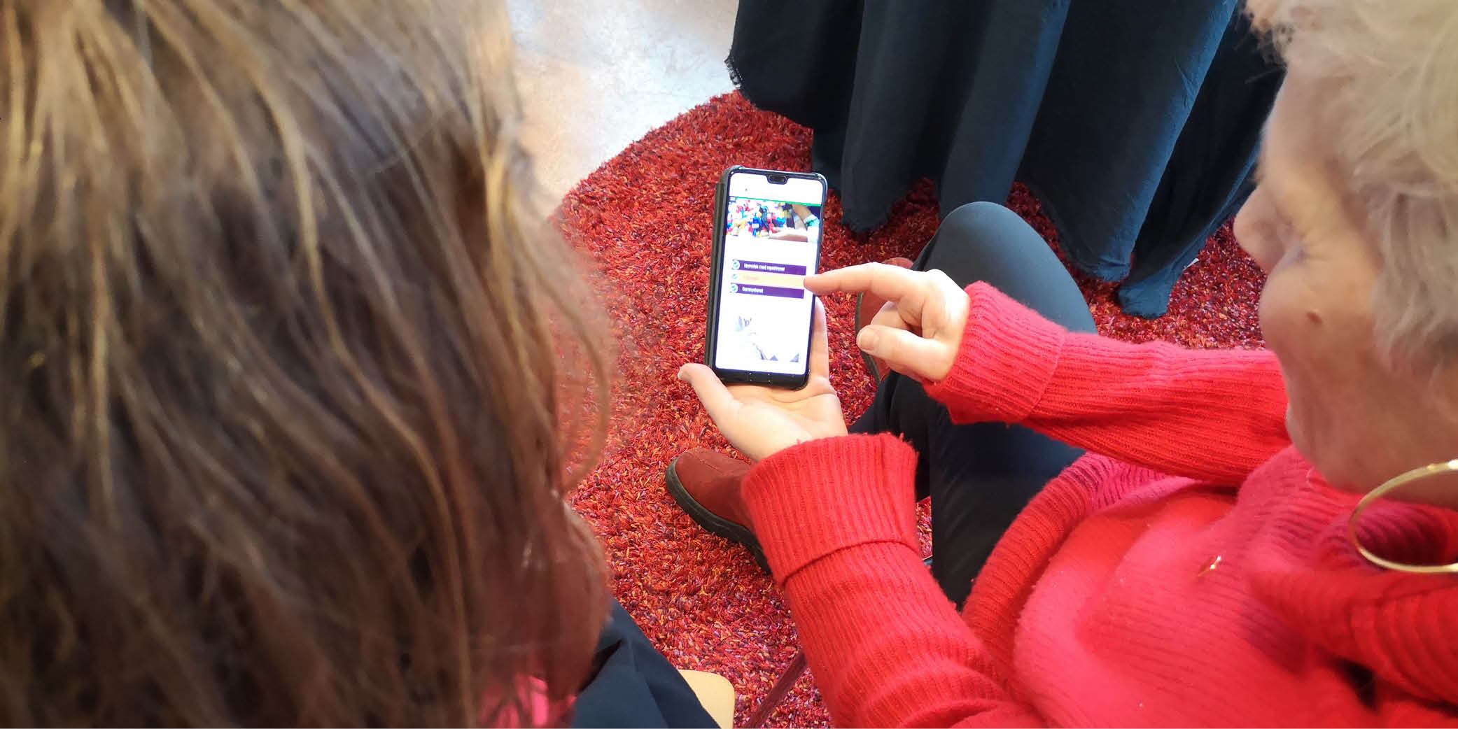 En kvinna visa en annan person något på en mobiltelefon