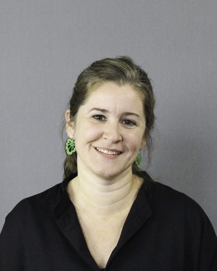 Isabelle som bär en svart skjorta och gröna örhängen.