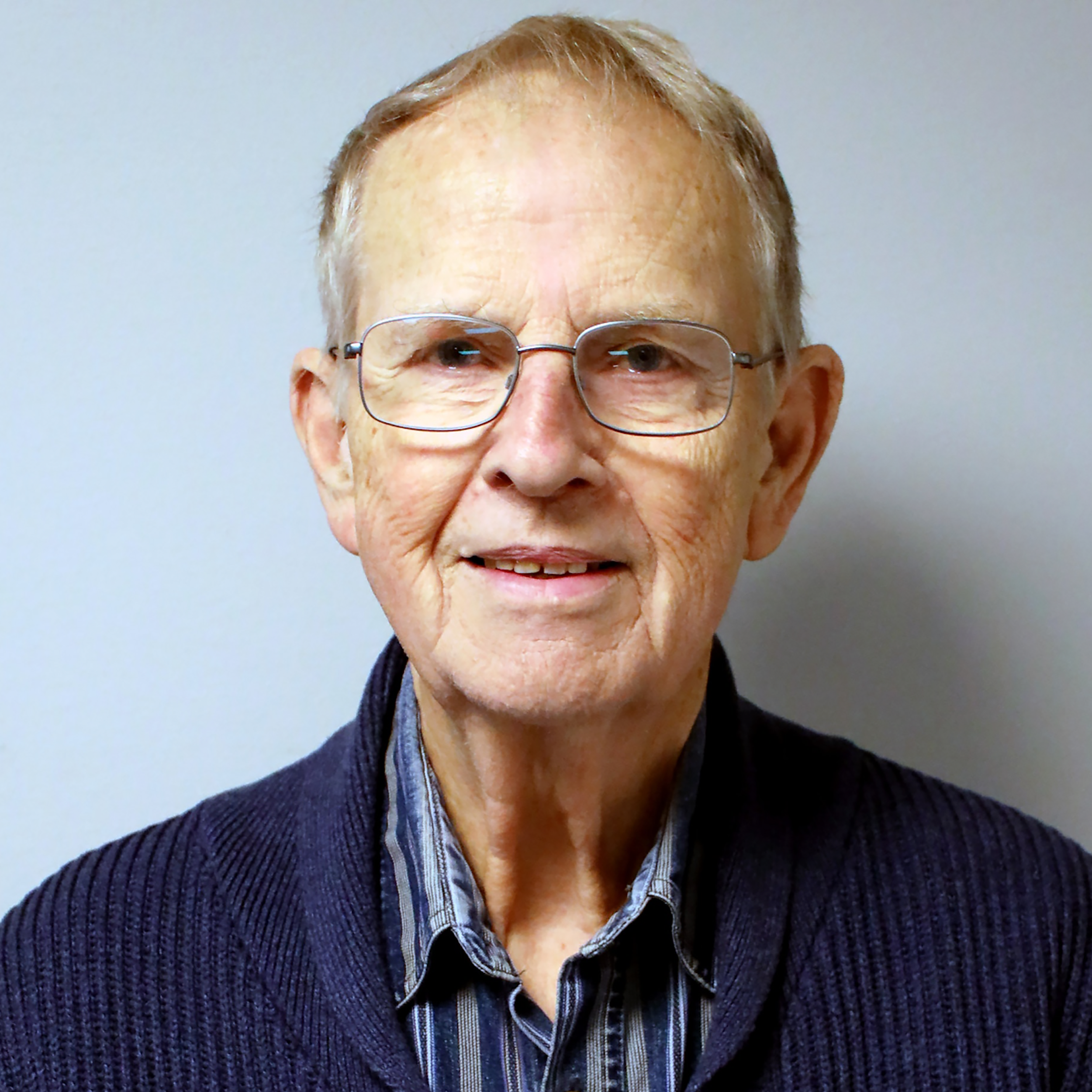 En äldre man med glasögon och tröja.