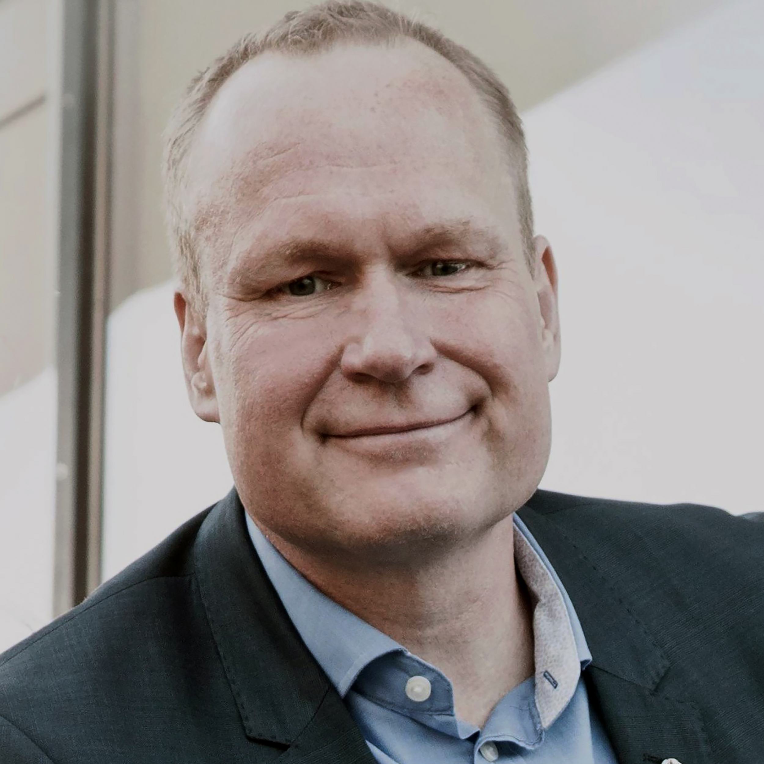 En man i en blå skjorta ler.