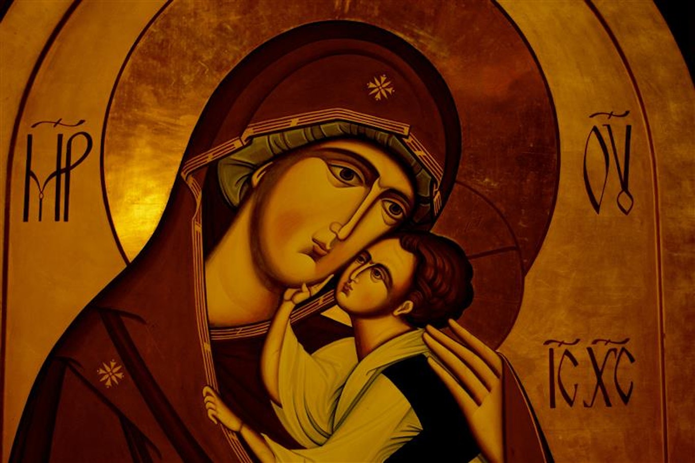 Ikon av Jungfru Maria som håller Jesusbarnet, med grekiska bokstäver på gyllene bakgrund.