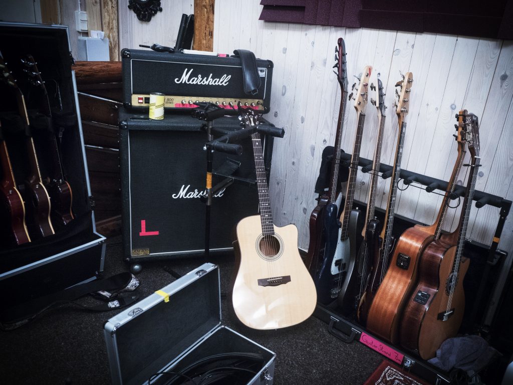 En musikstudio med gitarrer, en Marshall-förstärkare och fodral på ett heltäckningsmatta.