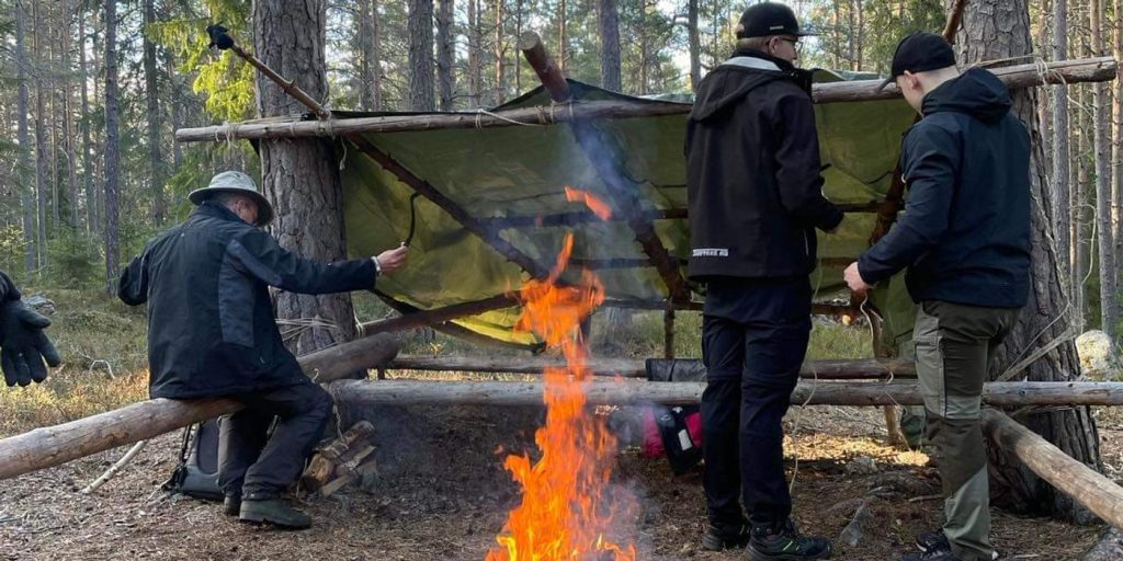Hannes Hedin, scoutledare, står framför en brasa.