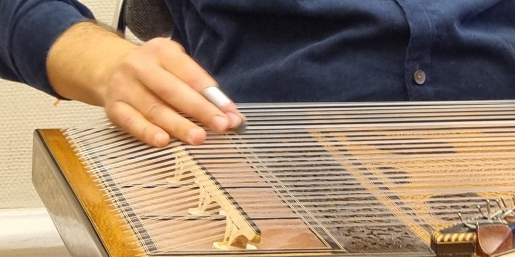 En man som sitter på en stol och spelar ett musikinstrument.