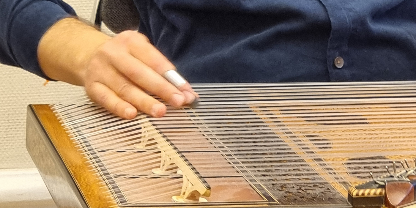 En man som sitter på en stol och spelar ett musikinstrument.
