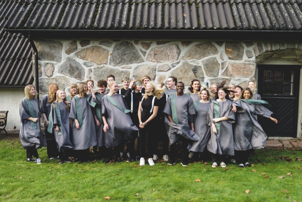 En gospelkör som står utomhus framför ett stenhus