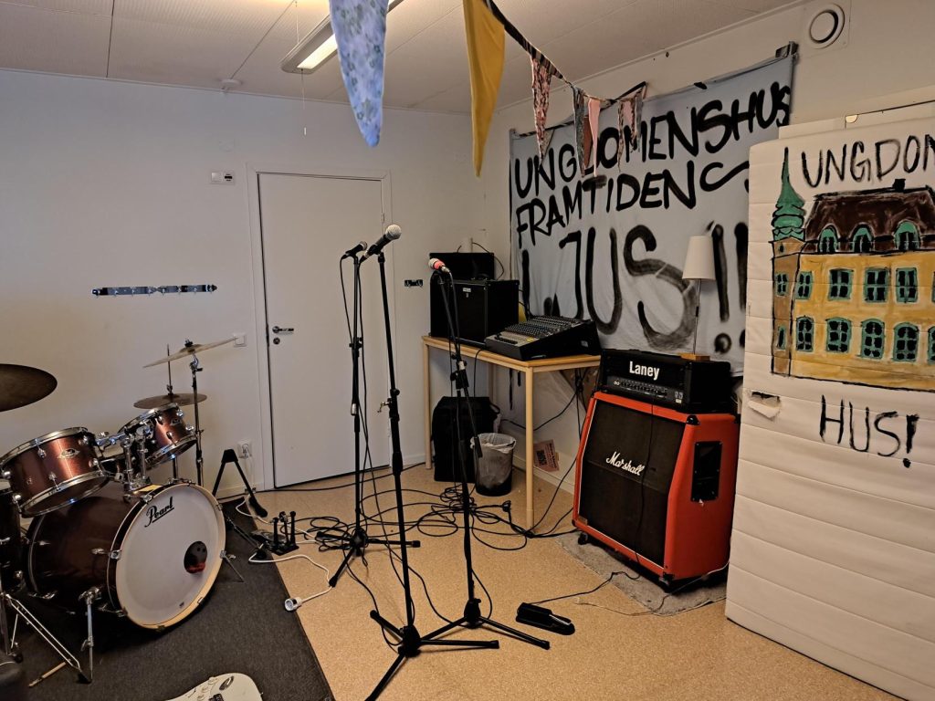 Ett övningsrum för ett band med trummor, mikrofoner, förstärkare och banderoller på väggarna.