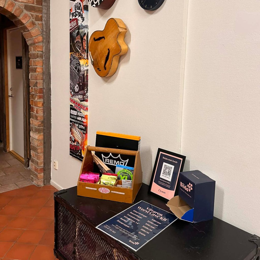 Ett bord med flygblad, en låda med förnödenheter, en donationslåda och affischer på en vägg i en korridor.