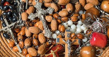 En hög med radbandspärlor med trä- och metallkors arrangerade på en vävd yta.