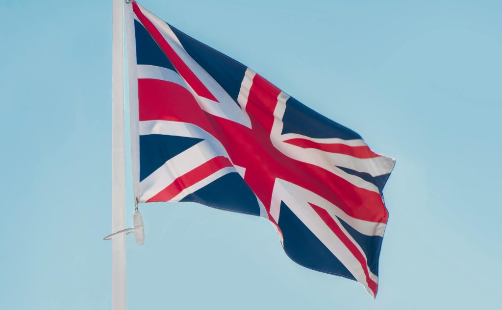 Storbritanniens flagga Union Jack vajar på en stång mot en klarblå himmel.