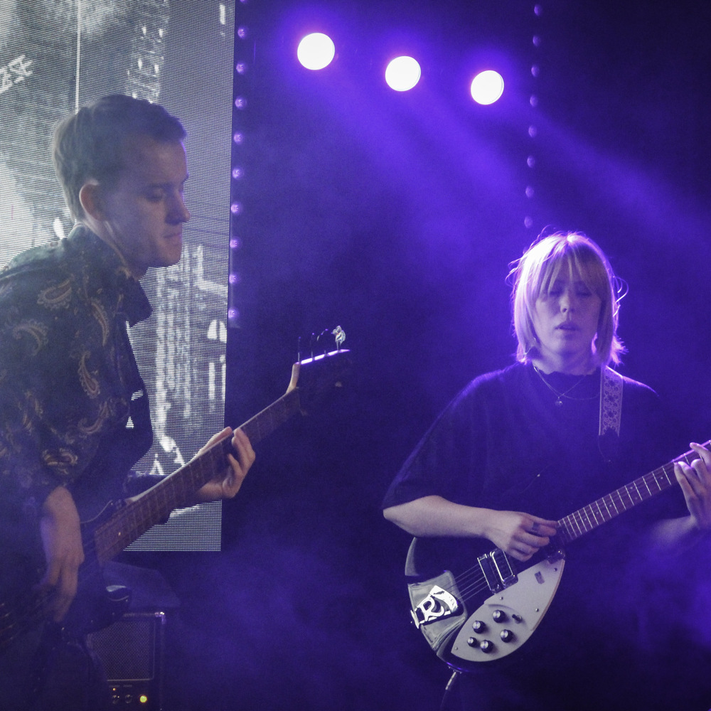 En man och en kvinna spelar gitarr på en scen.