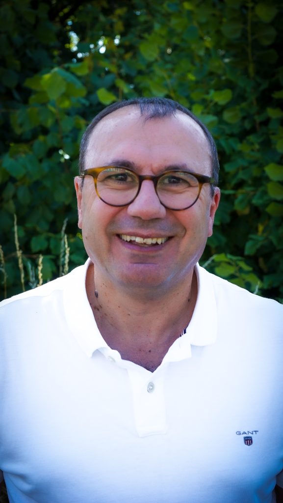 En man med glasögon som ler.