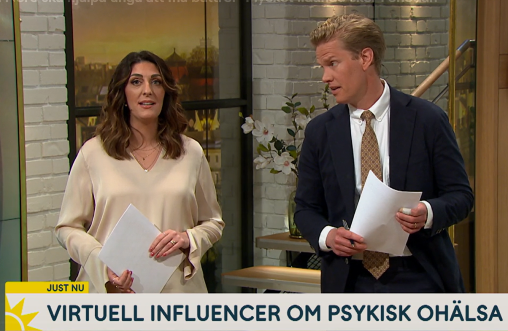Två nyhetsuppläsare håller i tidningar i en tv-studio.