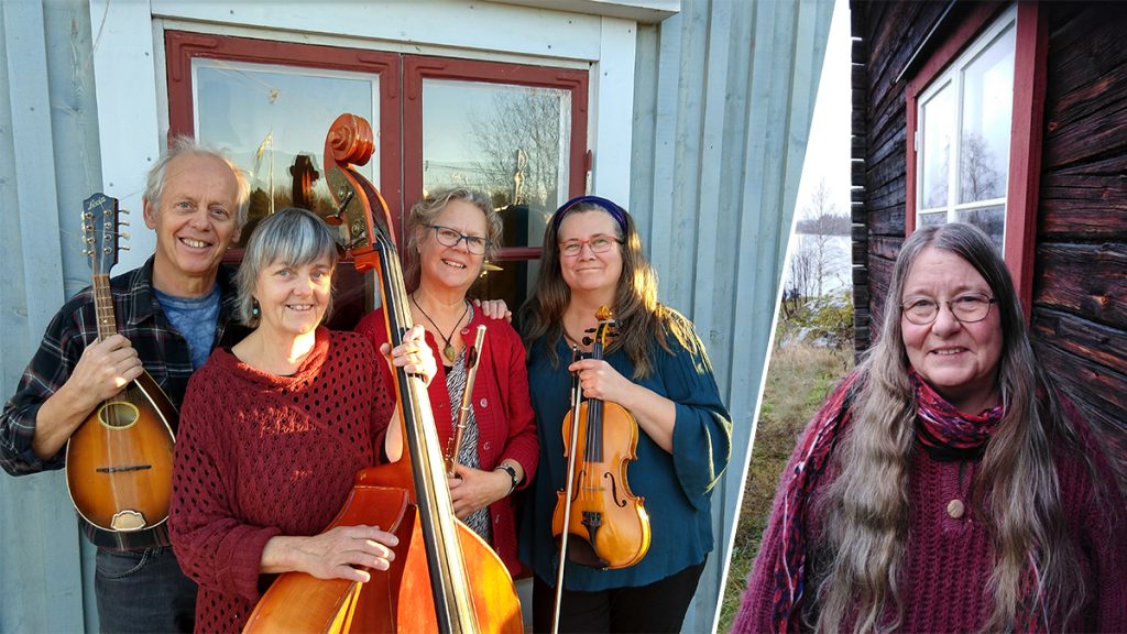 Fyra leende människor med musikinstrument och en kvinna med långt hår står vid en trävägg.