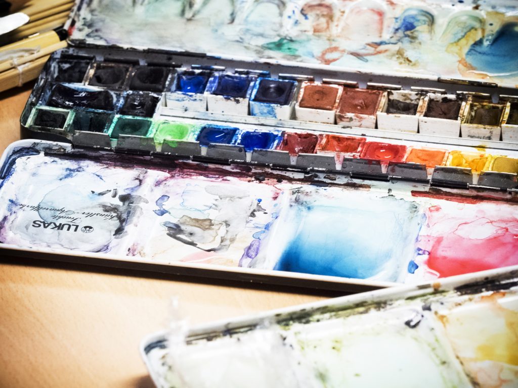 En låda med vattenfärger på ett träbord.