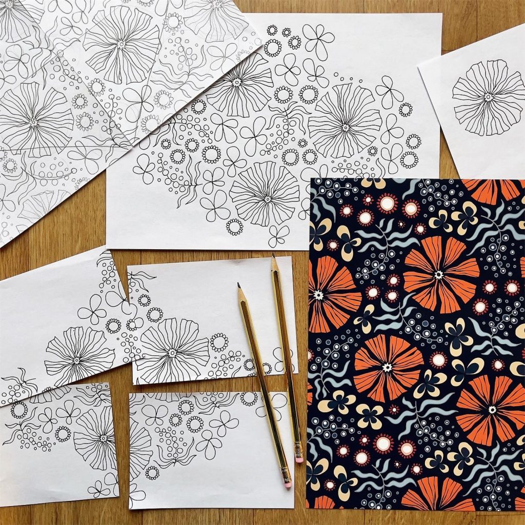 Svartvita blomskisser och pennor bredvid ett färdigt blommönster i orange, marinblå och grädde.