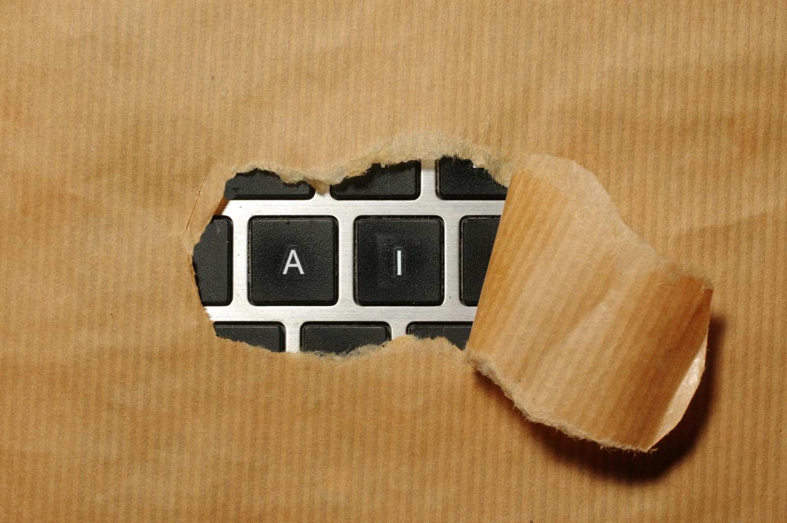 En sönderriven bit brunt papper avslöjar bokstäverna "A" och "I" på ett datortangentbord.