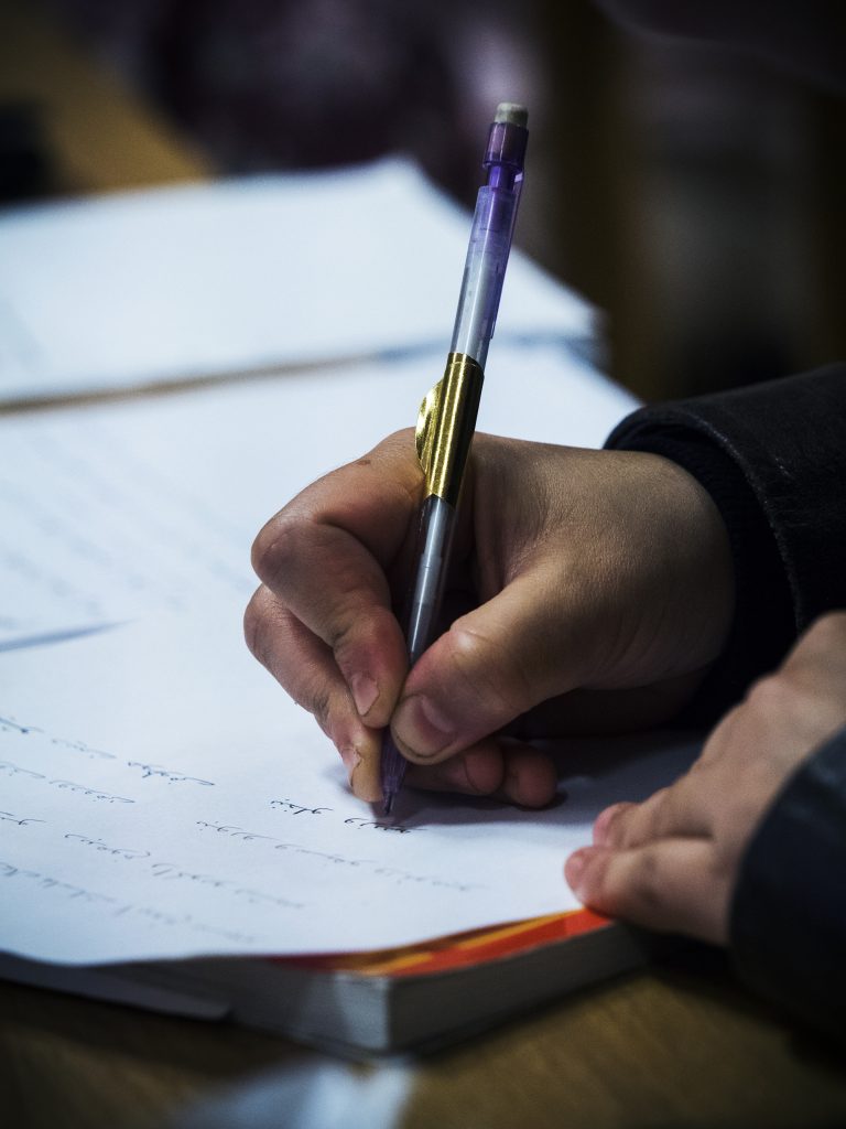 En person som skriver på ett papper med en penna.