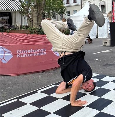 En person dansar breakdance på en svartvitrutig matta vid ett utomhusevenemang i Göteborg.
