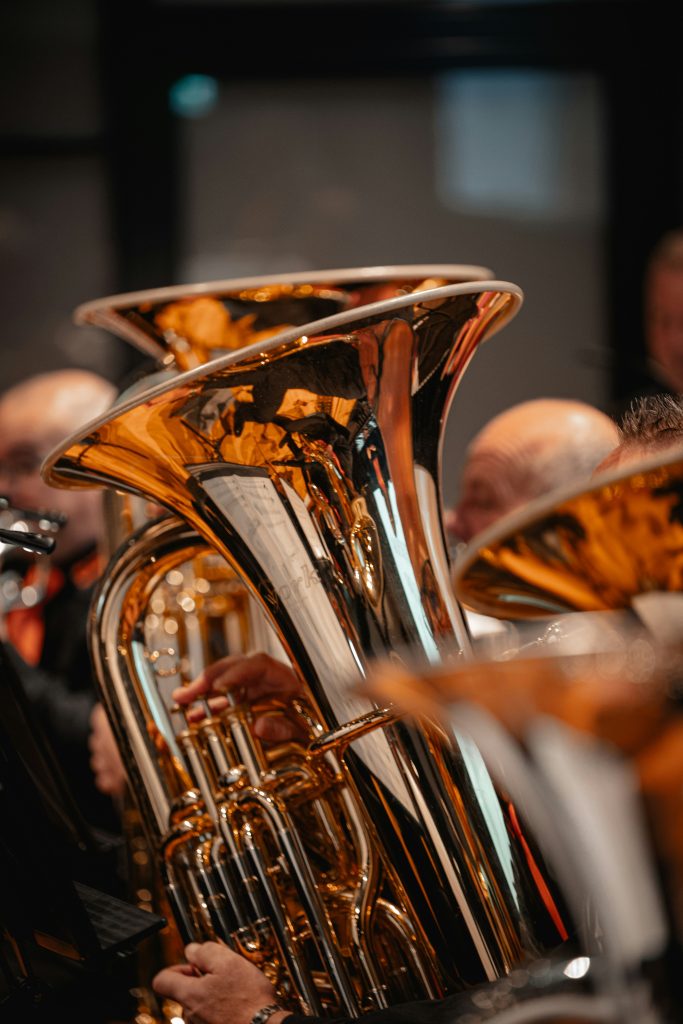 Musiker som spelar på blanka mässingstubor i en orkester, med synliga reflexer på instrumentens ytor.