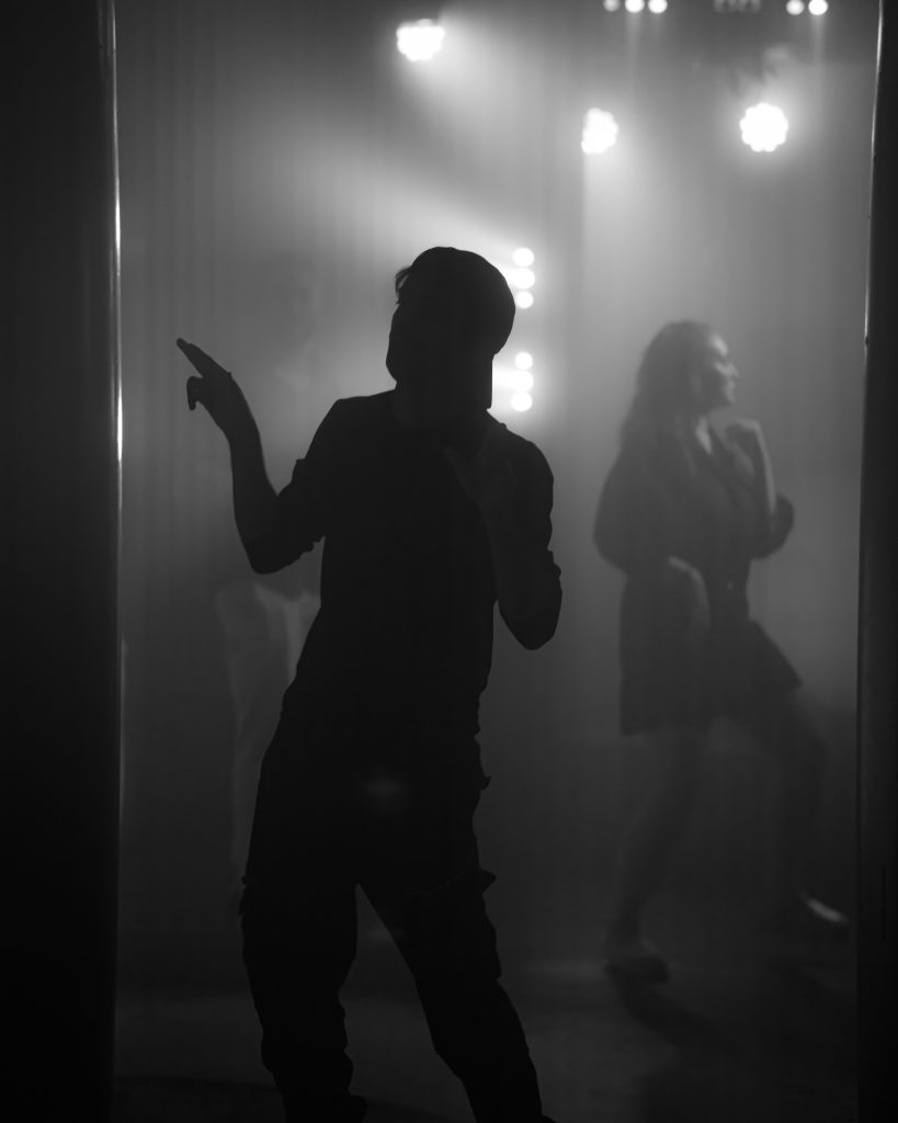 En man står framför en spegel i ett mörkt rum.