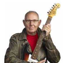 Äldre man i brun skinnjacka håller i en elgitarr och tittar in i kameran.