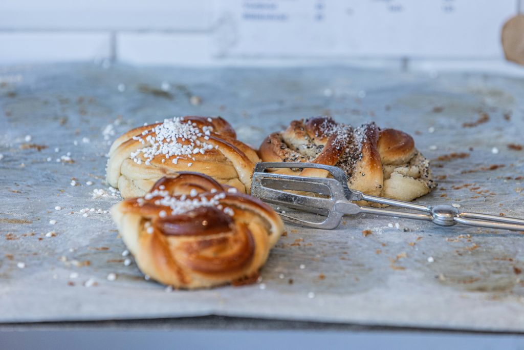 Tre söta bullar på pergamentpapper, med en tång bredvid, beströdda med socker.