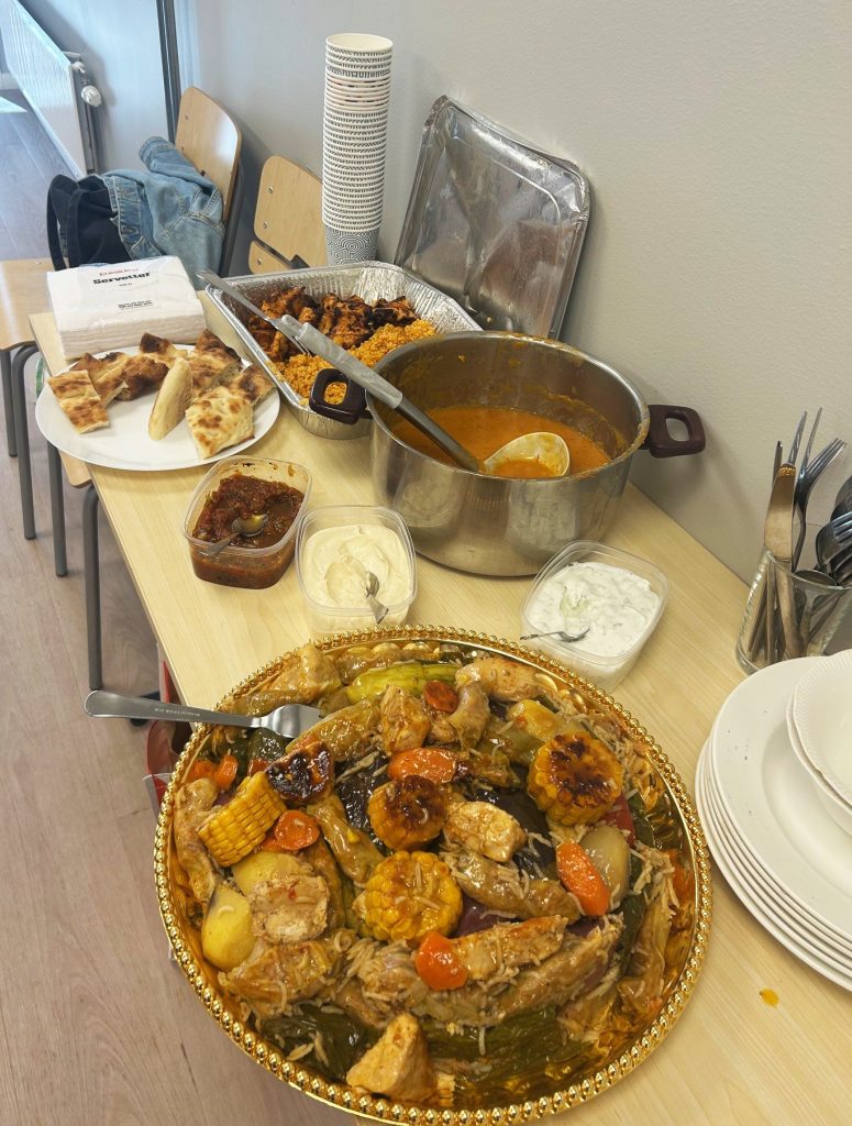 Ett bord med olika rätter, bland annat gryta, ris, bröd, såser och staplade tallrikar och redskap.