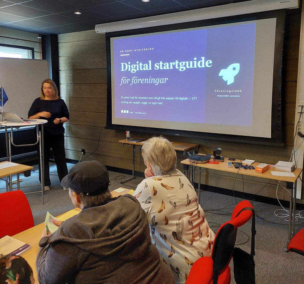 En kvinna presenterar ett bildspel "Digital startguide för föreningar" för personer som sitter i ett klassrum.