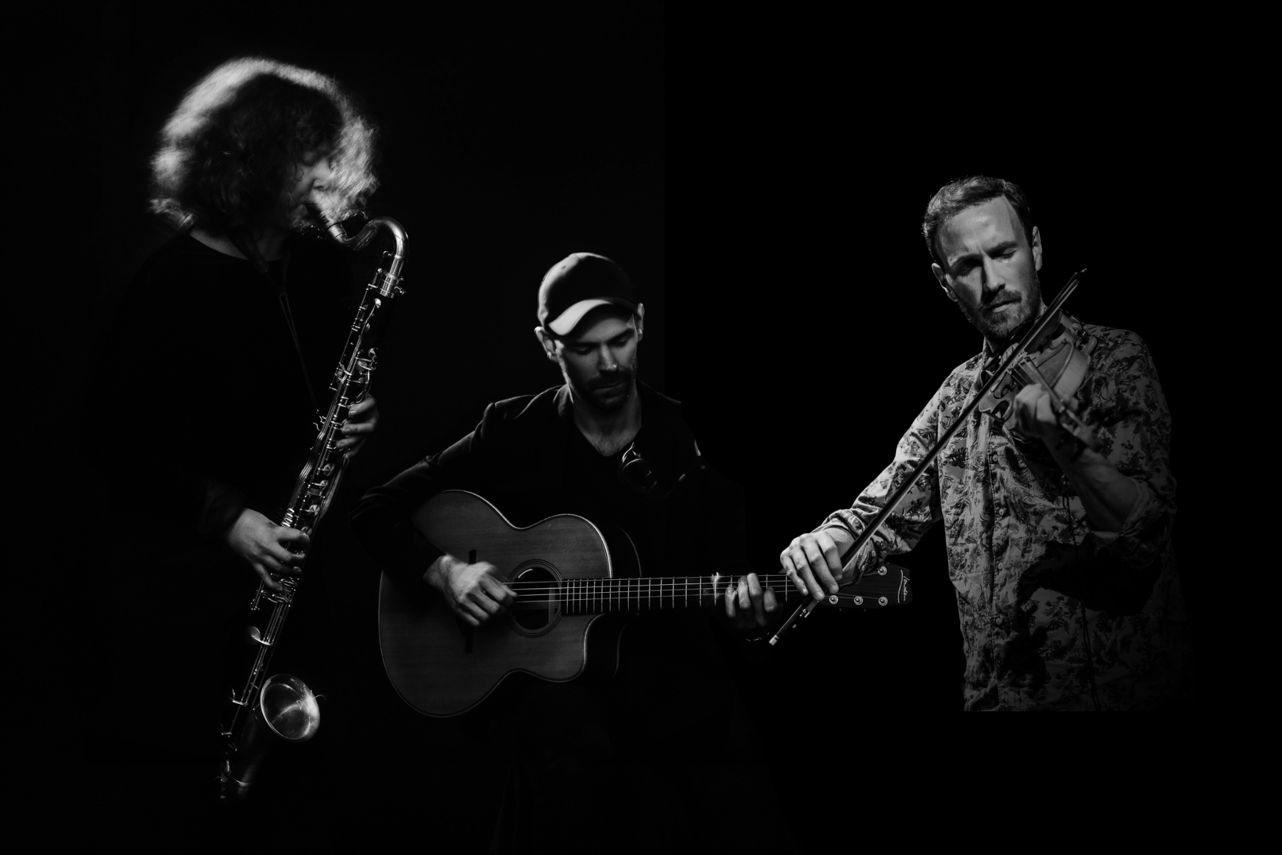 Tre musiker som spelar instrument: saxofon, gitarr och violin, i dramatisk svartvit belysning.
