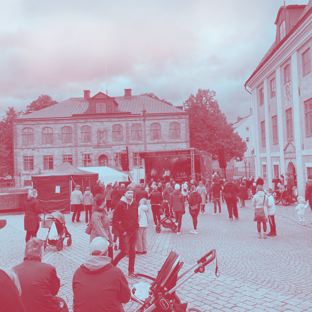 Folk hade samlats på ett torg med kullersten för att titta på en scenföreställning; området omges av historiska byggnader.