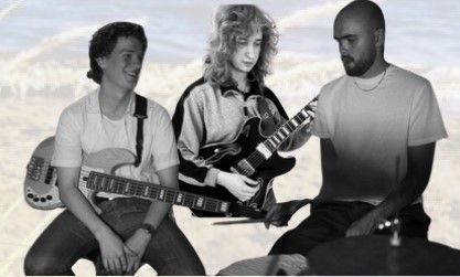 Tre personer som spelar instrument: två med gitarr och en på trummor, sitter tillsammans och interagerar.