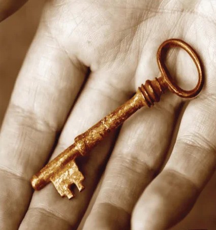 En persons hand som håller i en gammaldags, vintage nyckel av mässing.