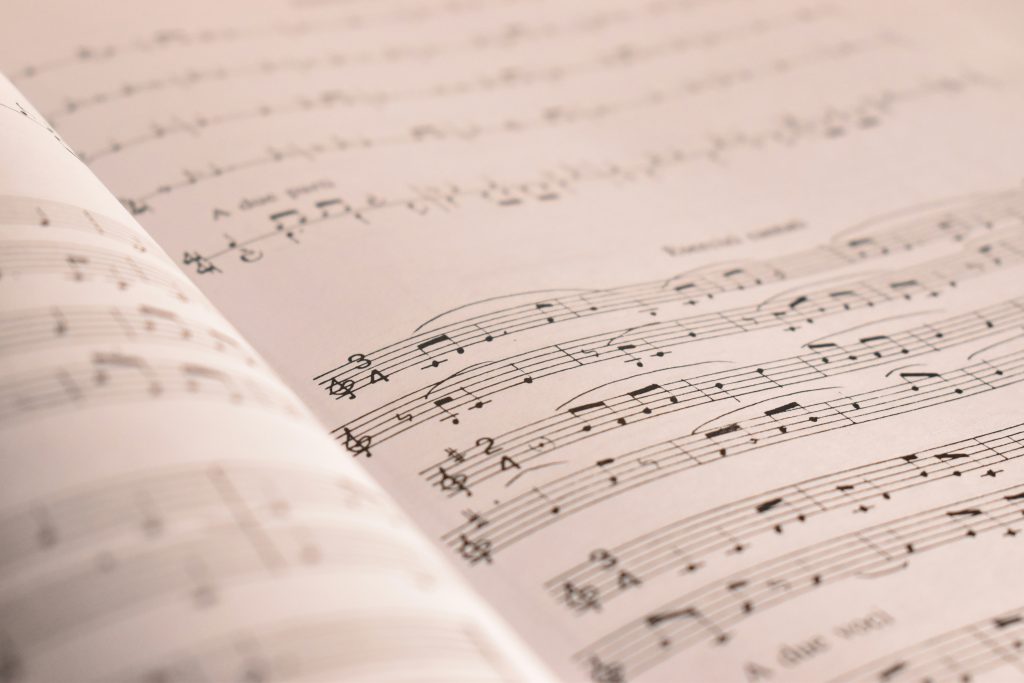 Närbild av öppna noter med musikaliska noter och notsystem på gräddfärgade sidor.