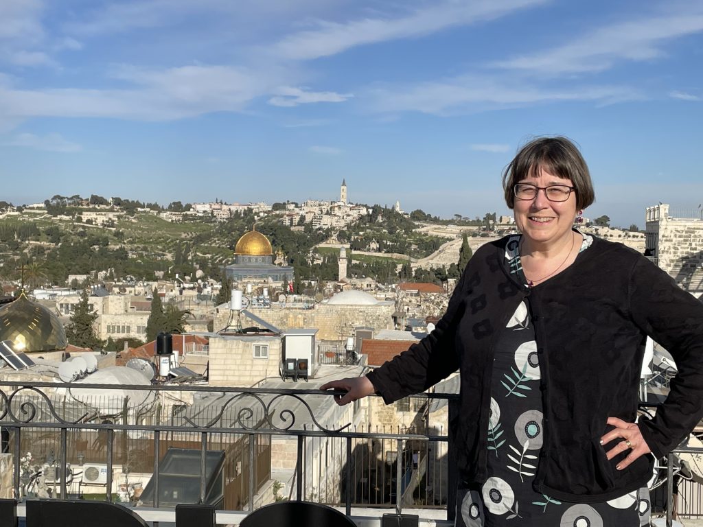 En kvinna står på en balkong med utsikt över Jerusalem, och Klippkupolen syns i bakgrunden.