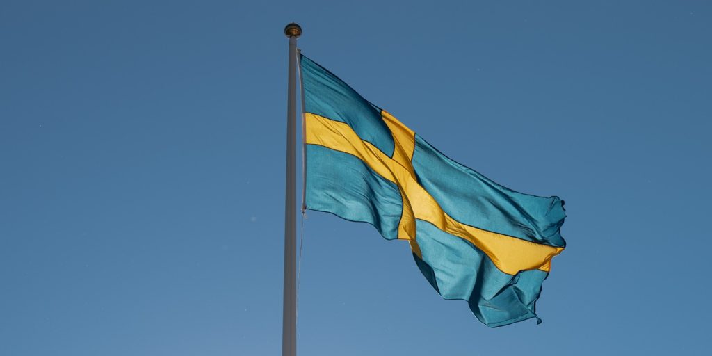 En blå och gul flagga som vajar på himlen.