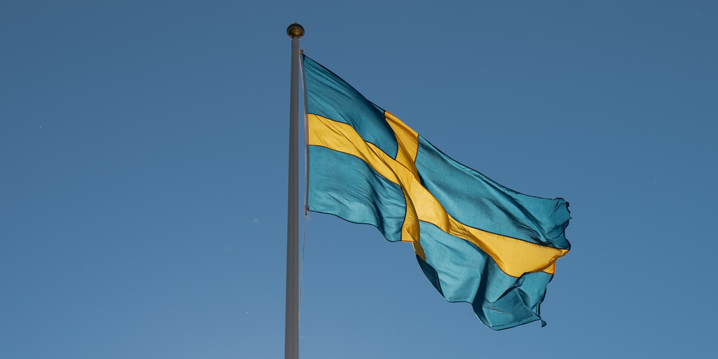 En blå och gul flagga som vajar på himlen.