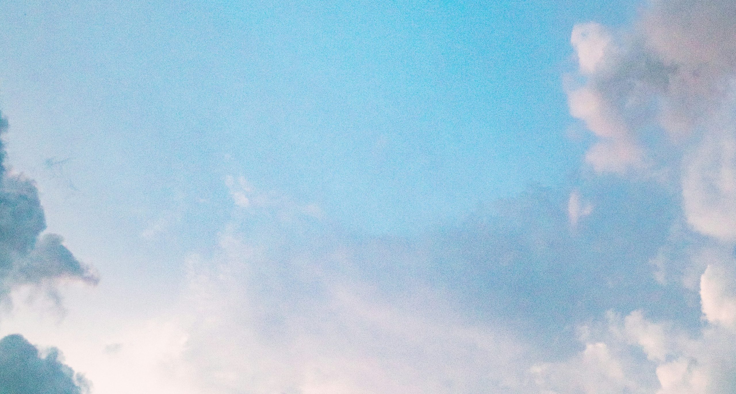 En ljusblå himmel med mjuka vita och rosa moln utspridda över landskapet.