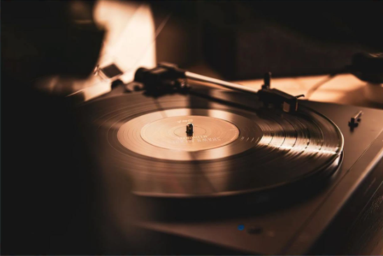 Närbild av en snurrande vinylskiva på en skivspelare, i mjukt ljus i en varm och stämningsfull miljö.