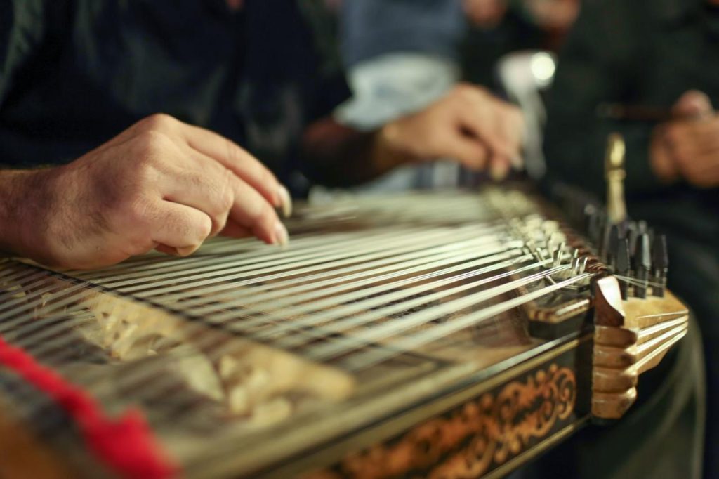 Händer som spelar på en qanun, ett traditionellt stränginstrument.